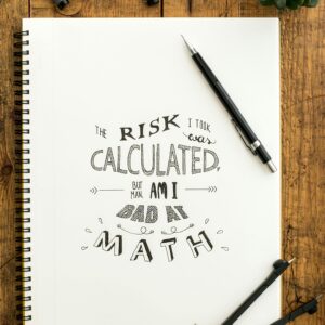 Flat lay of hand lettering on sketchbook with art tools on wooden desk
