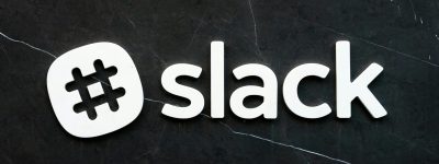 Close-up of Slack logo with hashtag symbol on a dark textured background, emphasizing digital communication.